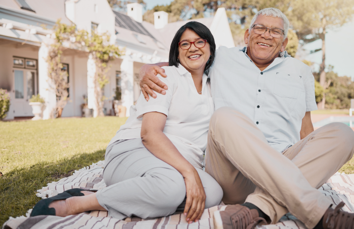 Happy senior couple standing together outside their house, enjoying the moment